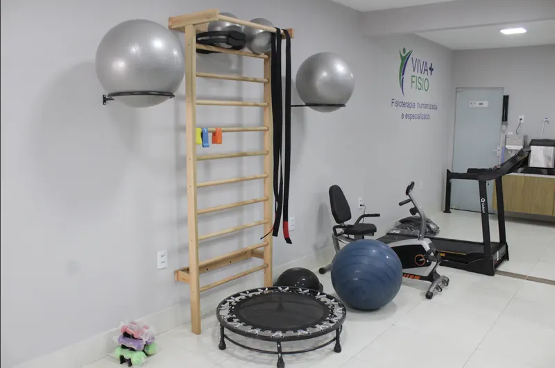 Sala de exercícios terapêuticos da Viva+ Fisio, com espaldar, bolas suíças, esteira e bicicleta