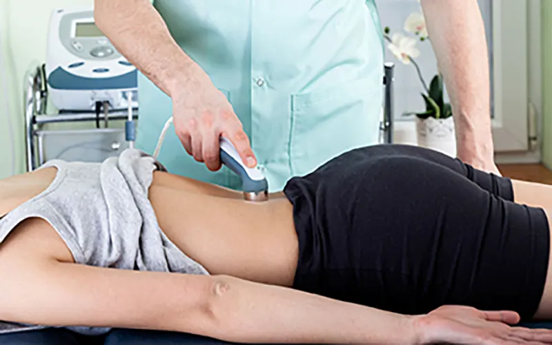 Eletrodos de eletroterapia posicionados na lombar de paciente em sessão de fisioterapia